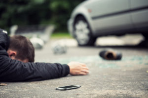Personal Injury Lawyer Elk Grove, IL - man laying face down on ground next to stopped crashed car